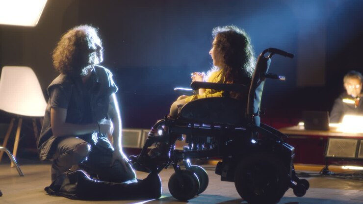 Photographer interacting with a child in a wheelchair in a photo studio