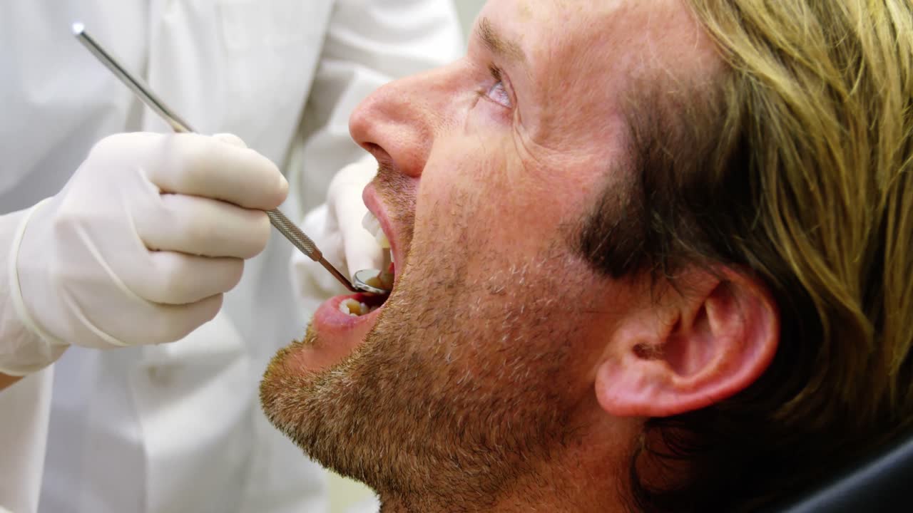 una dentista examinando a un paciente con herramientas dentales