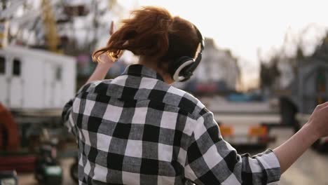 Happy-brunette-dancing-and-jumping-in-crazy,-funny-dances-outside-on-the-street.-Wearing-a-plaid-shirt-and-sunglasses.-Sunny,-light-day