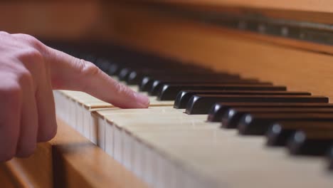 a finger playing a single note on an old piano