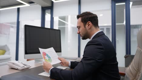 lawyer or businessman sits at a desk, analyzing a colorful chart document in a modern office environment with focused attention