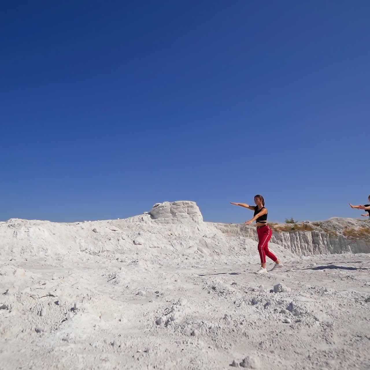 Contemporary girly dance studio performing outdoors on white rocks. Group of modern sportive dance performers