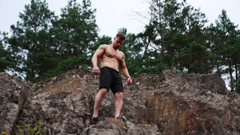 sportsman wearing black shorts climbing by the rocks. athlete demonstrates his muscles. low angle view.
