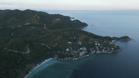 retiro aéreo sobre koh tao, tailandia al atardecer, mostrando las exuberantes colinas de la isla, las turbinas eólicas y la costa con aguas azules tranquilas y paisajes tropicales