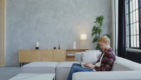 man with arm injury working from home on couch