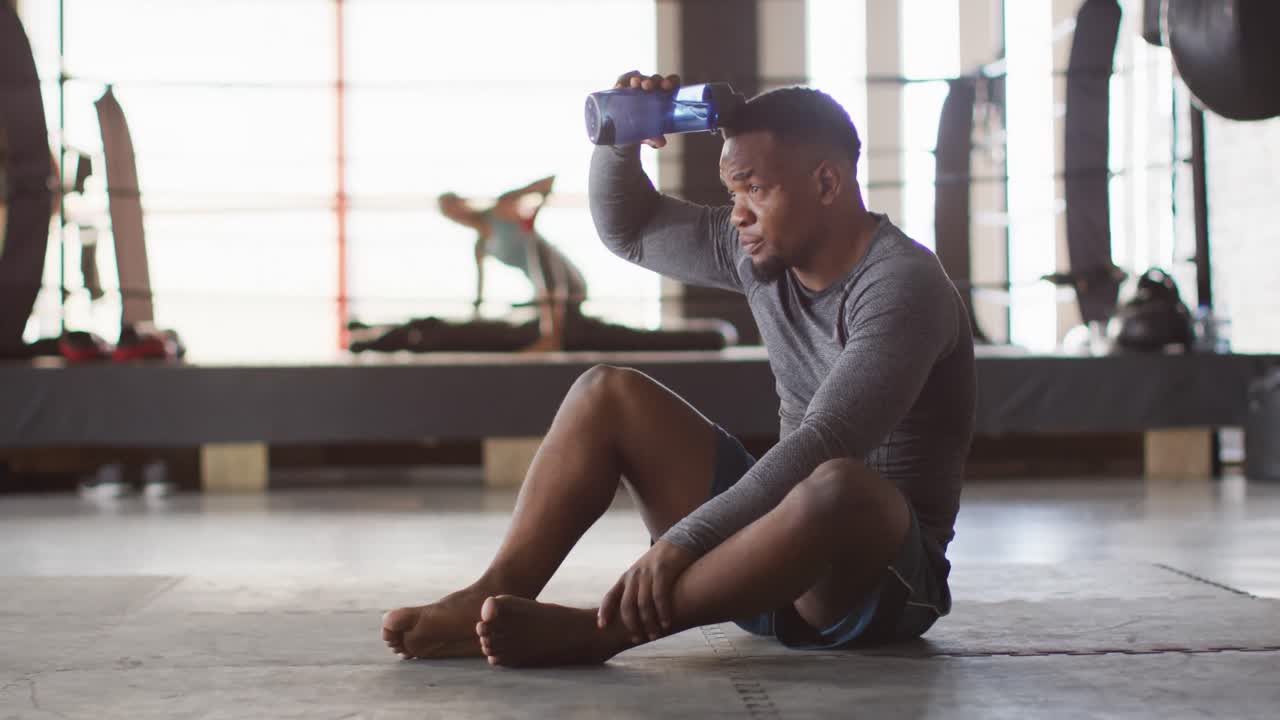 Video of fit and tired african american man resting after training at gym