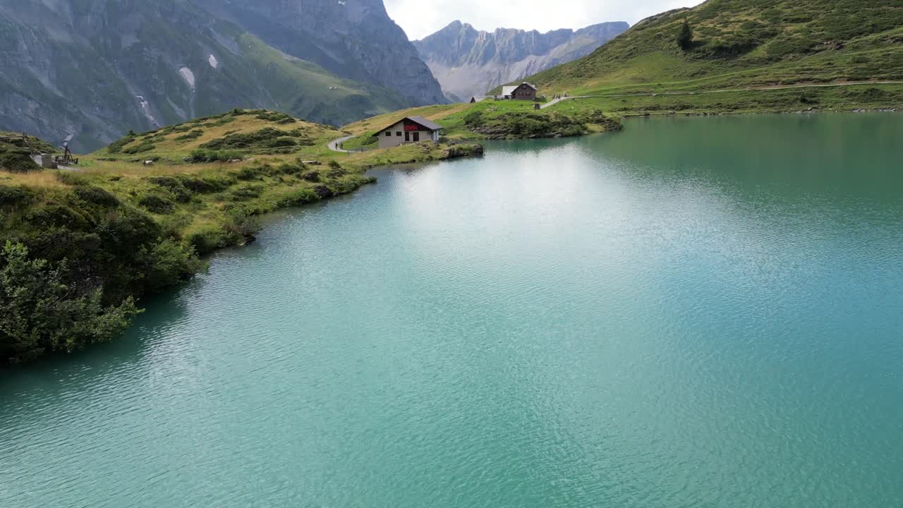 fpv drone vista aérea de una cabaña junto a un lago alpino en los alpes suizos, obwalden, engelberg