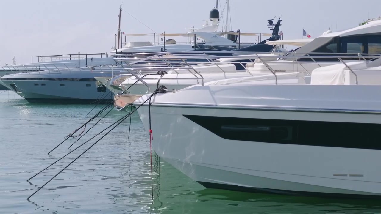 Primo piano della prua di uno yacht con cime d'ormeggio tra superyacht ormeggiati in un porto turistico, Golfe-Juan, Francia.