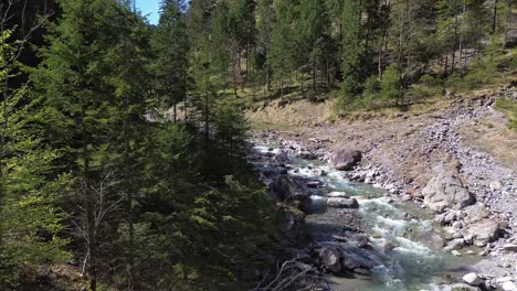 Drones-Vuelan-Sobre-El-Río-Con-Aguas-Cristalinas-De-Color-Turquesa-En-El-Valle-De-La-Montaña-En-Austria,-Europa