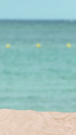 Vertical-Video-Summer-Holiday-Concept-With-Sandy-Beach-In-Foreground-Against-Sea-Background