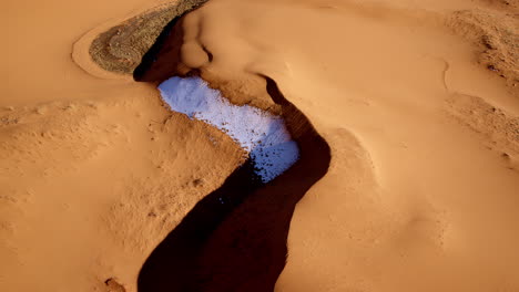 drone camera peers down at the undulating shapes and dreamy textures of the pink sands.