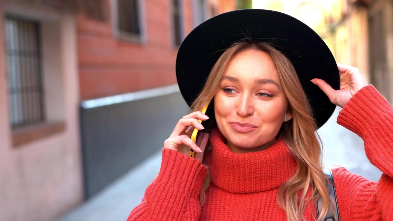 Donna bionda che parla al suo smartphone mentre cammina per strada.
