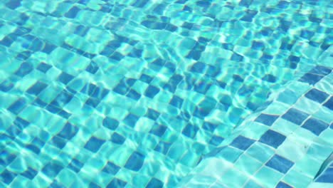 static shot of water reflecting in a blue checkered pool