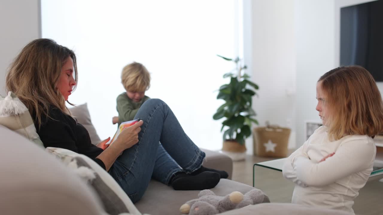 엄마  ⁇ 에 있는 슬픈 아이들이 태블릿을 탐색하고 있습니다.