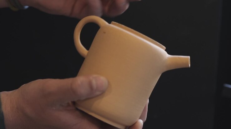 A potter makes a clay teapot with his own hands