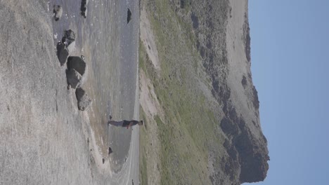 Ein-Junge-Entspannt-Sich-Am-Ufer-Eines-Sees-Mit-Grünen-Bergen-Und-Blauem-Himmel-In-Villa-Pehuenia,-Patagonien,-Argentinien