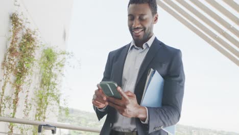 Glücklicher-Afroamerikanischer-Geschäftsmann,-Der-Sein-Smartphone-Nutzt-Und-Im-Büro-Feiert,-Zeitlupe