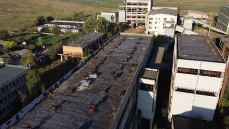 Approaching-drone-shot-of-run-down-buildings-of-a-rare-metals-enterprise-that-used-to-produced-materials-for-nuclear-energy,-located-in-Vadu,-Romania