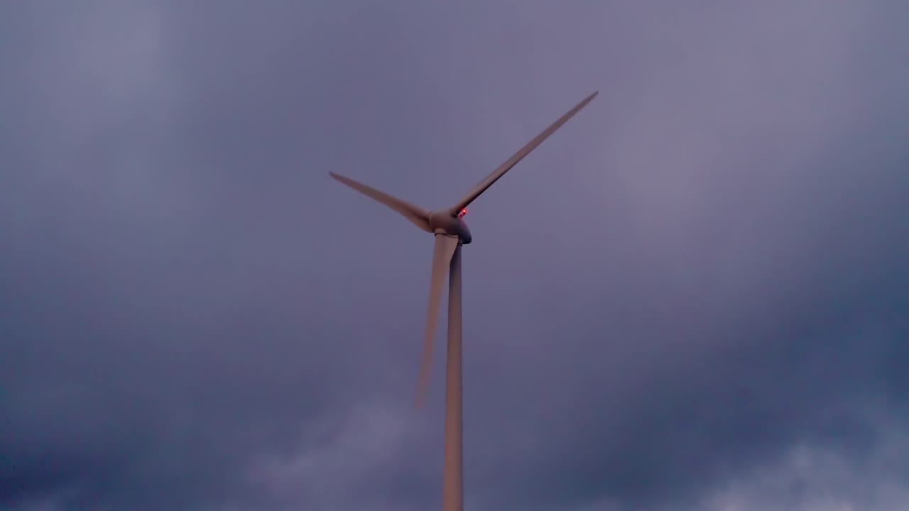 Turbina eolica ad asse orizzontale sulla cresta della Serra da Boneca nella regione Centro del Portogallo, che domina la valle del fiume Mondego al tramonto, mentre ruota e produce energia, scatto statico in silhouette