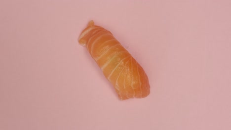 un rollo de sushi girando sobre un fondo rosado