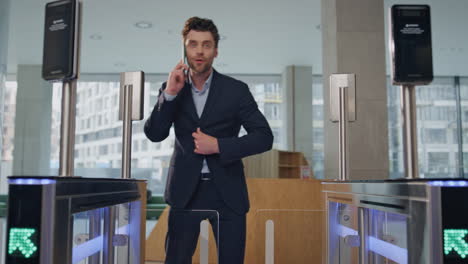 hombre confundido caminando turnstile oficina hablando teléfono inteligente. hombre saludando a la pantalla