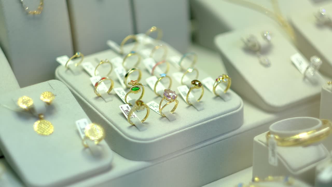 hay pendientes de oro y joyas en la ventana de la joyería jwe