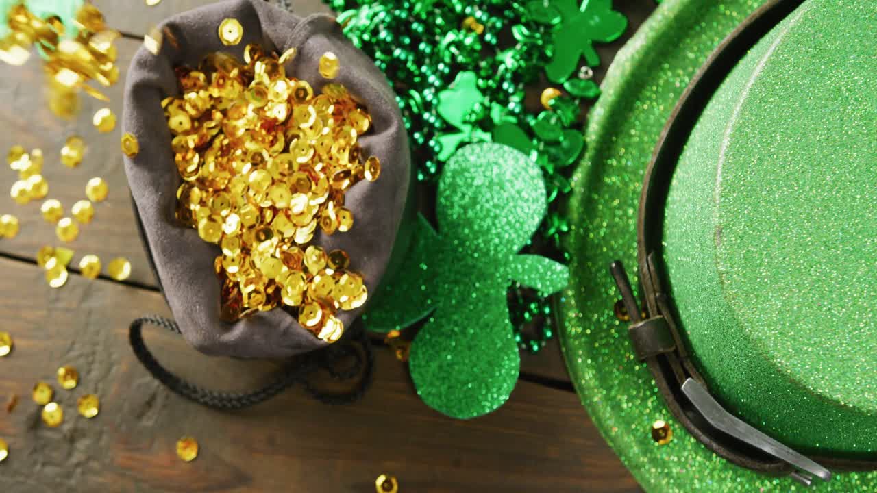 Video of st patrick's green hat, shamrock and gold sequins on wooden background