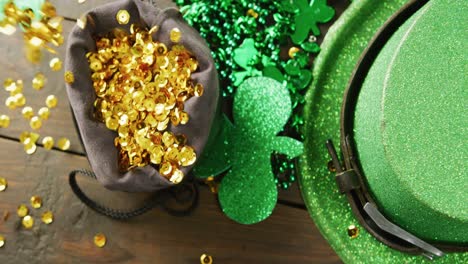 Video-of-st-patrick's-green-hat,-shamrock-and-gold-sequins-on-wooden-background