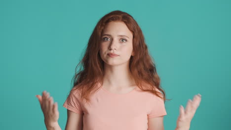 redheaded girl looking at camera on turquoise background.