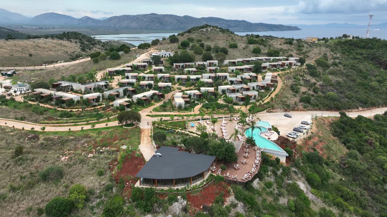 Aerial orbit view of contemporary villas and resort amenities in Albania, nestled amidst scenic hills, designed for an exceptional tourism experience.