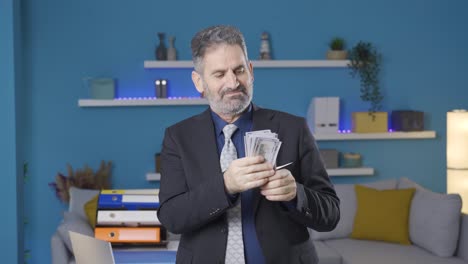 successful and ambitious businessman looks at the money he earns and is proud of himself.