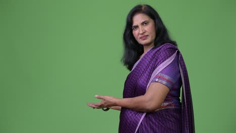 mujer india hermosa madura mostrando algo a la espalda con sari ropa tradicional