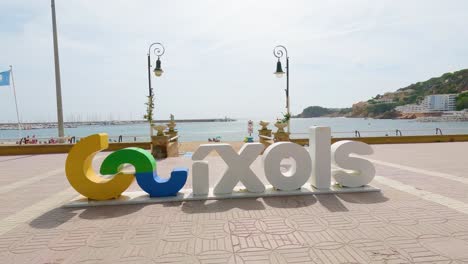 Sant-Feliu-de-Guíxols-on-the-Costa-Brava-of-Gerona-Spain-tourist-town-sign-closeup-with-beach-background