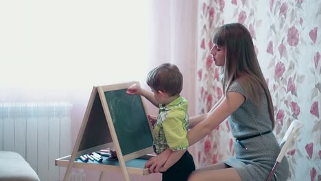 Mutter-Hilft-Sohn,-Sonnenstrahlen-Auf-Eine-Tafel-Zu-Zeichnen