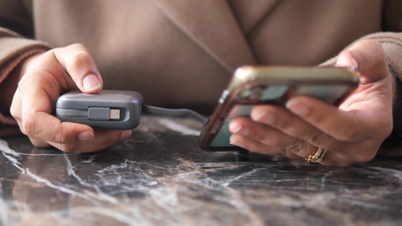 Persona che usa lo smartphone mentre tiene un power bank portatile