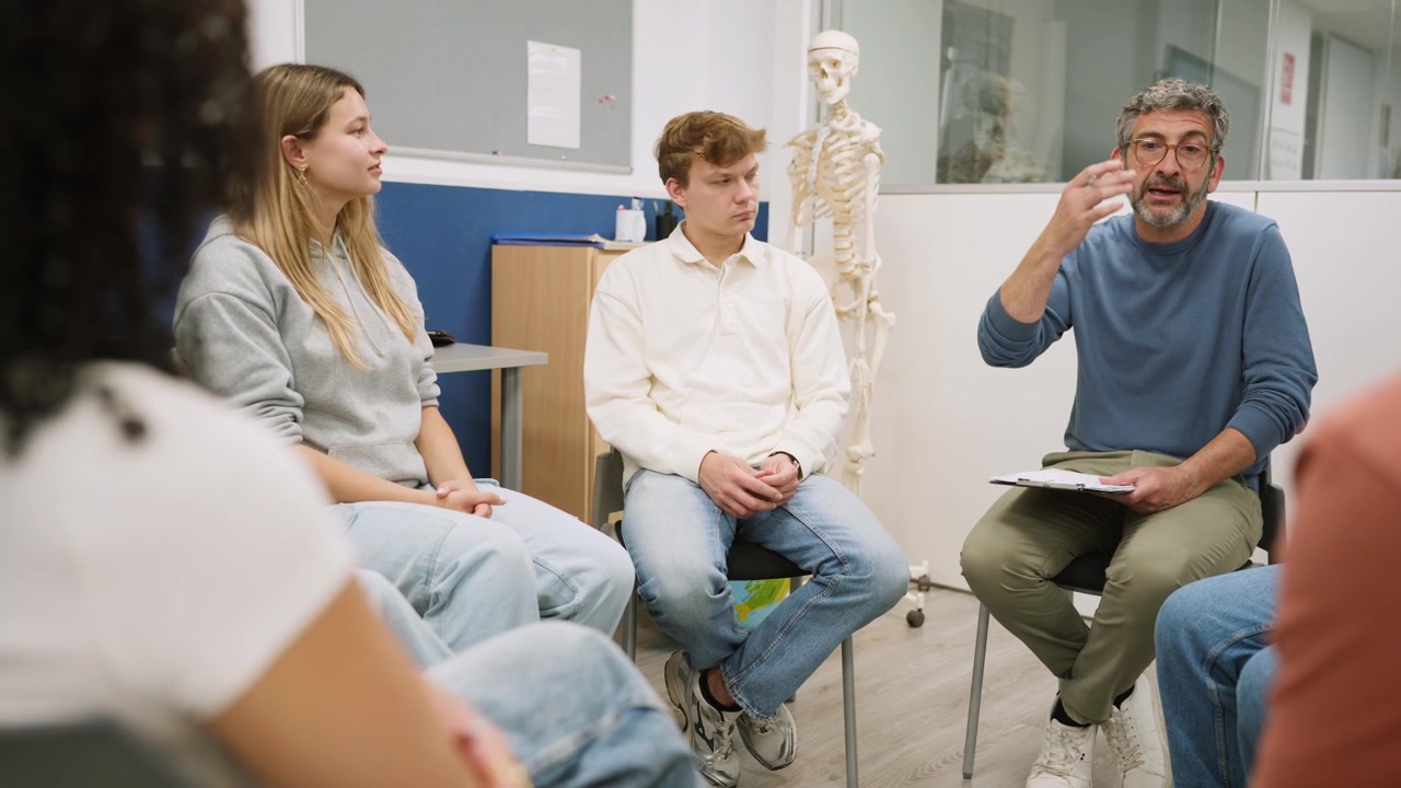 Lærer leder gruppediskussion, og elever klapper i klasseværelset.