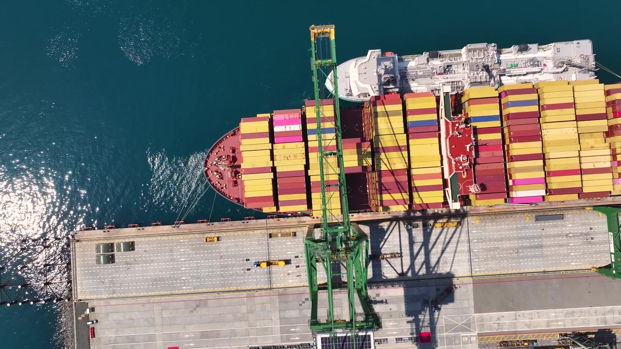 Large cargo ships at port unload containers as cranes operate. Shipping congestion affects global trade. Import export activities face delays and challenges at maritime facilities.