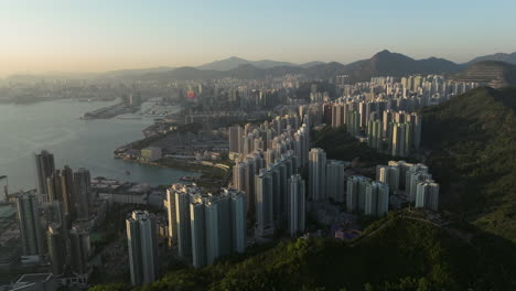 High-modern-buildings-in-Hong-Kong-illuminated-during-Golden-Hour-between-the-high-mountains-in-the-backdrop