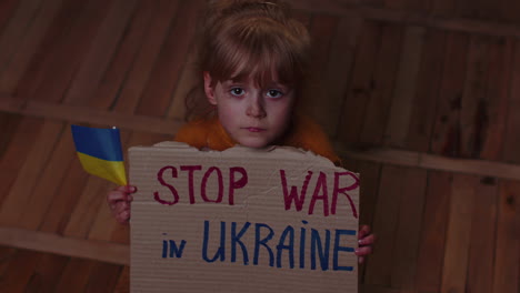 Afraid-Ukrainian-girl,-inscription-massage-Stop-War-In-Ukraine-hiding-from-bombing-attack-at-home