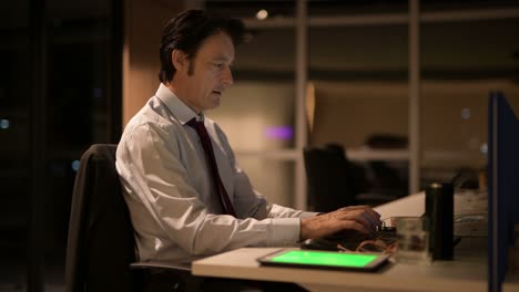 mature businessman sitting and working in office at night