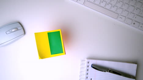 yellow post it with chroma key falling on office desk