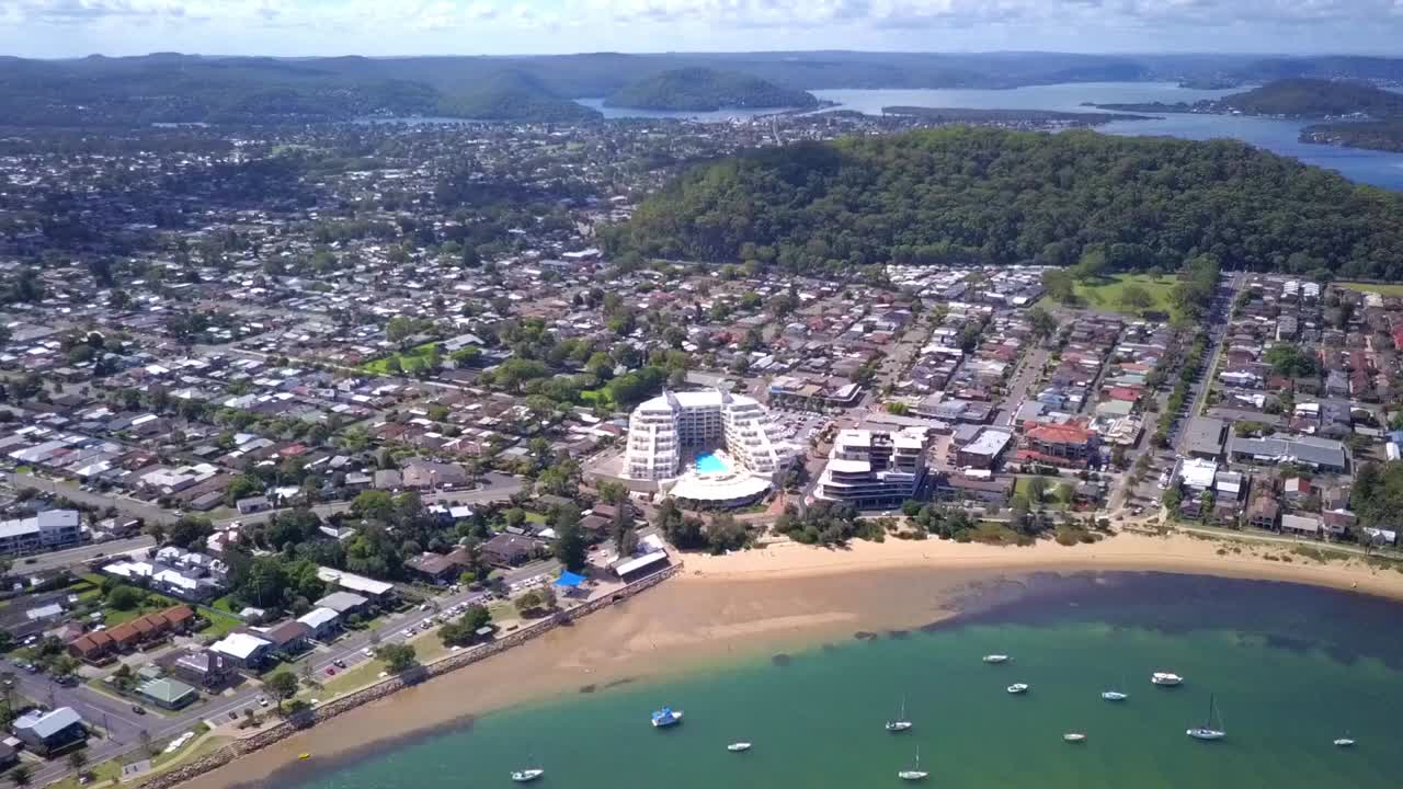 Pull away shot of coastal suburb in Sydney with white sand blue water tropical beach with waterfront houses. Ettalong, Australia.