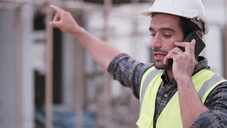 ingeniero civil caucásico o contratista o capataz que trabaja en un sitio de construcción de viviendas, use el teléfono inteligente hablando y explicando con el equipo sobre la forma de trabajo o hablando con la sociedad sobre el progreso del proyecto.
