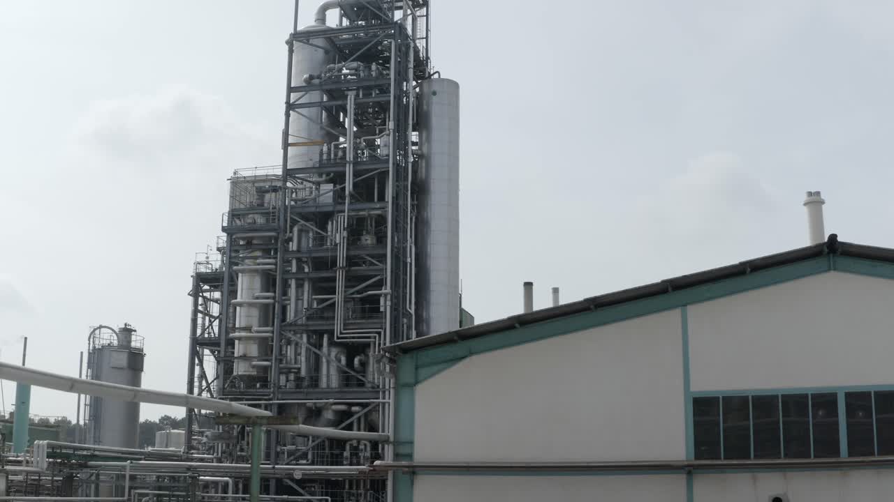 Tall industrial processing unit behind factory building, overcast sky, Veille-Saint-Girons, France