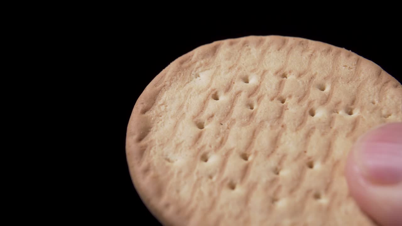 Round crispy cookies in hand on a black background