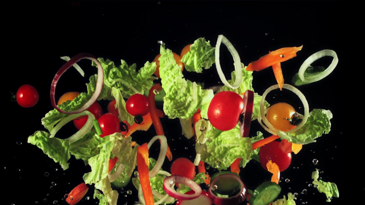 Verdure vivaci per insalata che volano con schizzi d'acqua al rallentatore.