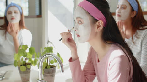 applying face mask, asian mother and daughter enjoying skincare routine together in bathroom