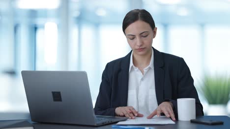 serious indian female manager working on laptop