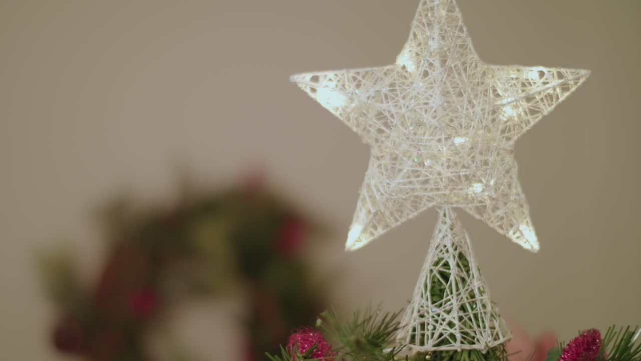 una persona pone una estrella en un árbol de navidad