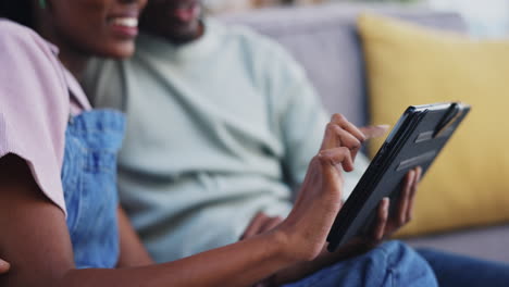 hands, tablet and a happy black couple on the sofa